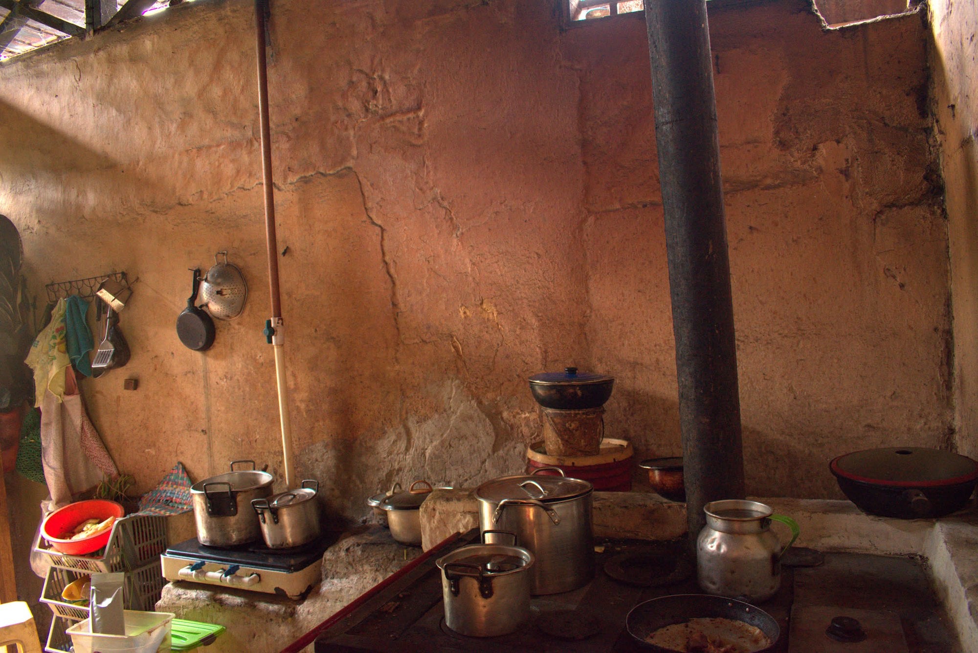 A wood-fired farm kitchen with enamel pots and a hand grinder