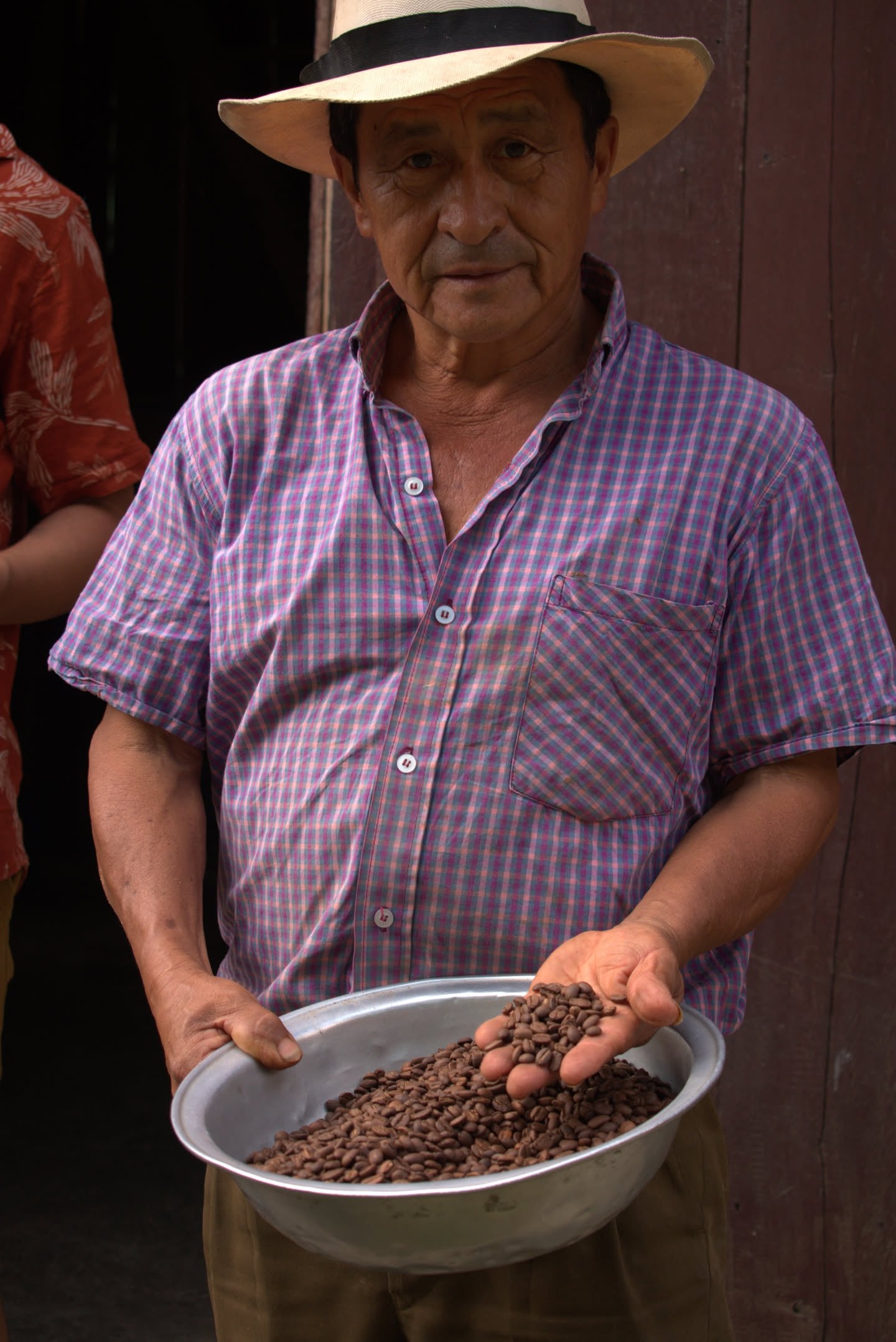 León Campo holding a tray of roasted coffee, a handful in his hand