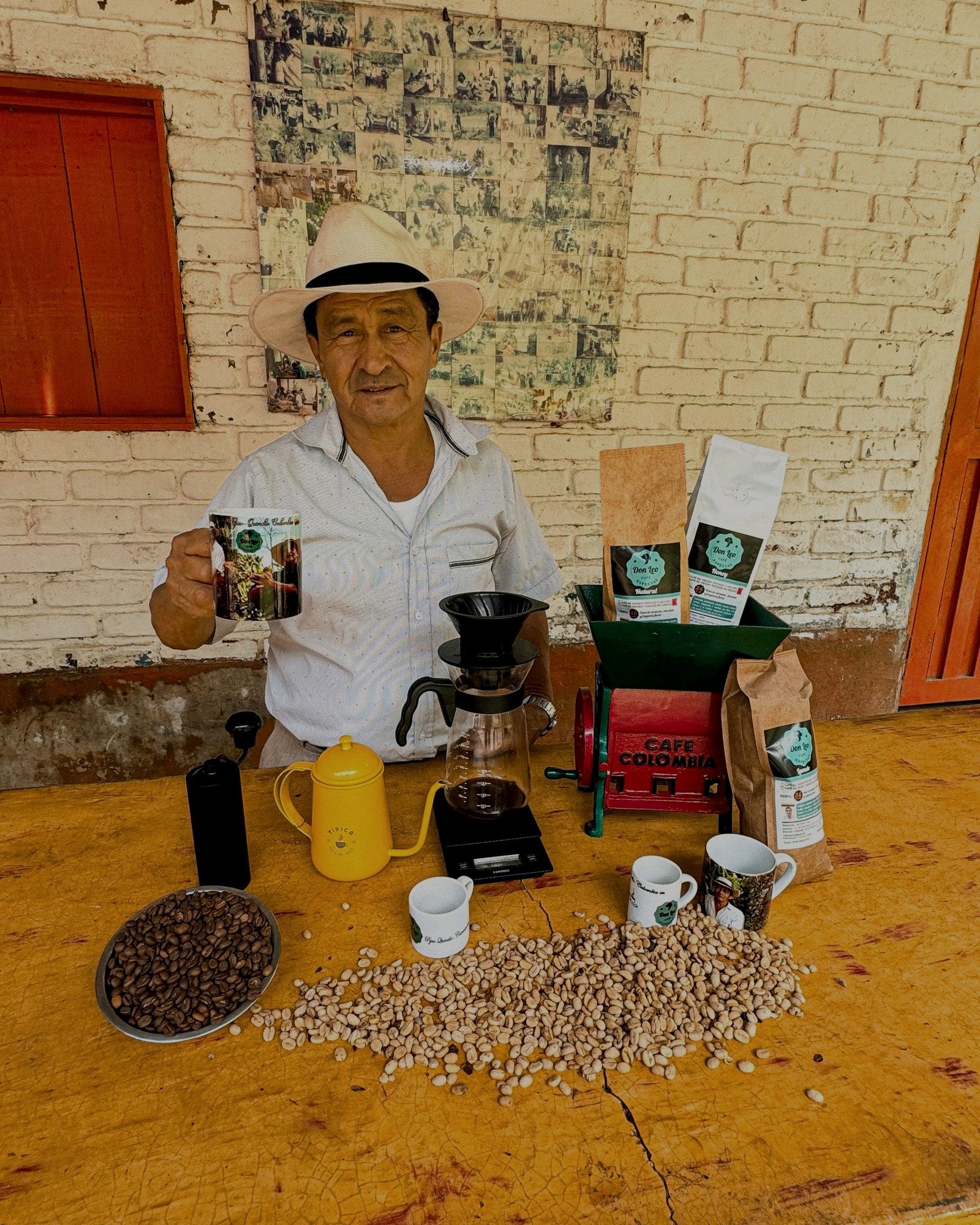 León Campo raising a cup of coffee at his stand, with the grinder and the bags behind him